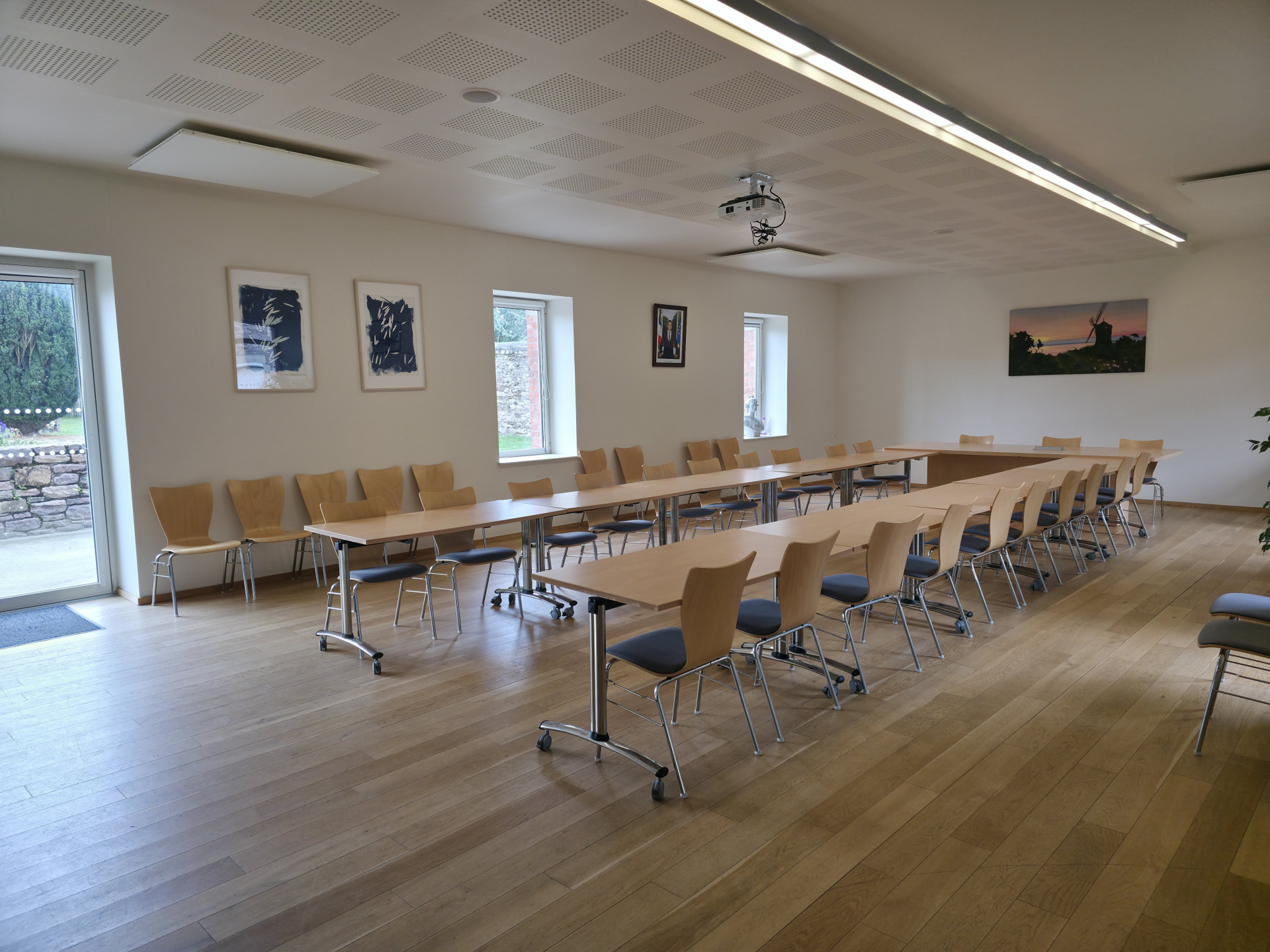 Salle de réunion avec tables, chaises et tableau blanc.