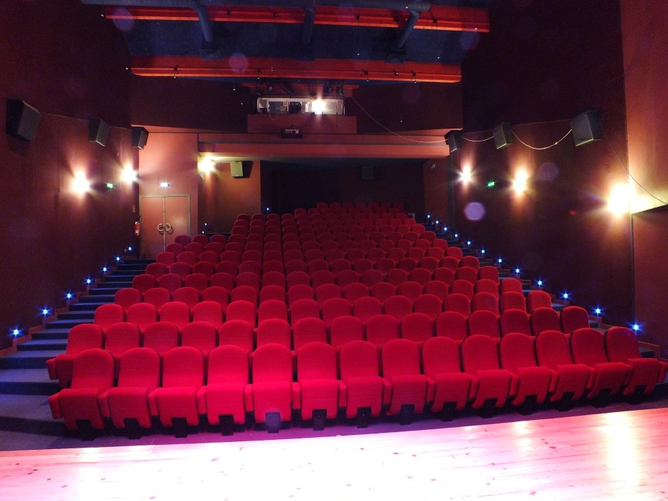 Salle de cinéma avec sièges, projecteur, éclairage et scène.
