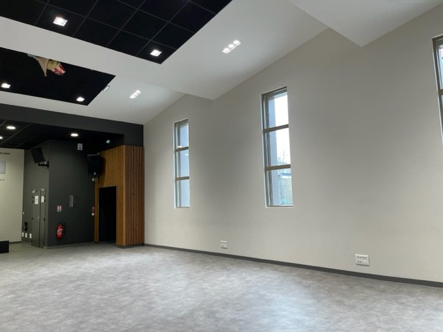 Pièce vide avec fenêtres, éclairage encastré, portes, et interrupteurs muraux.