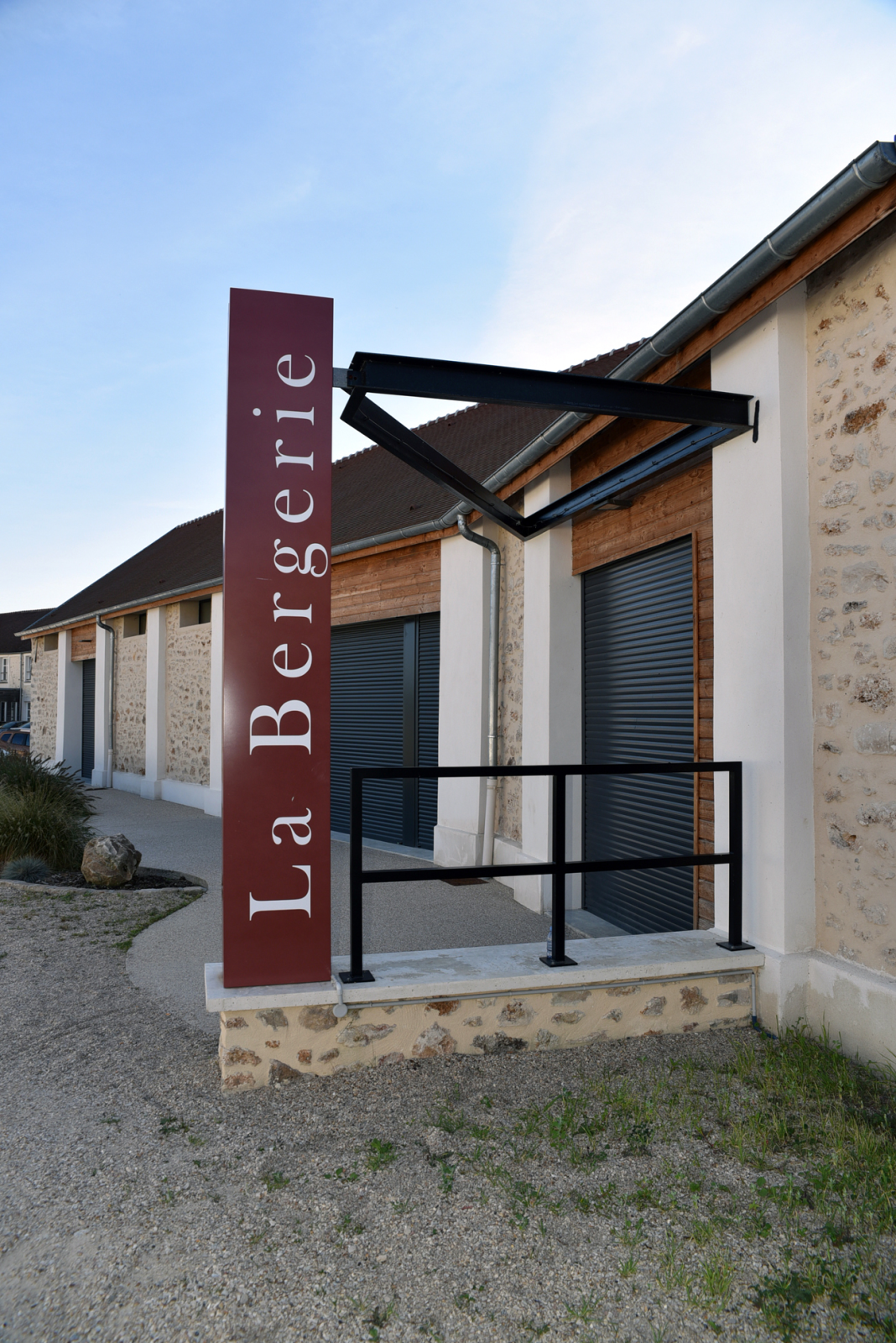 Bâtiment avec enseigne "La Bergerie", rampes et volets roulants.