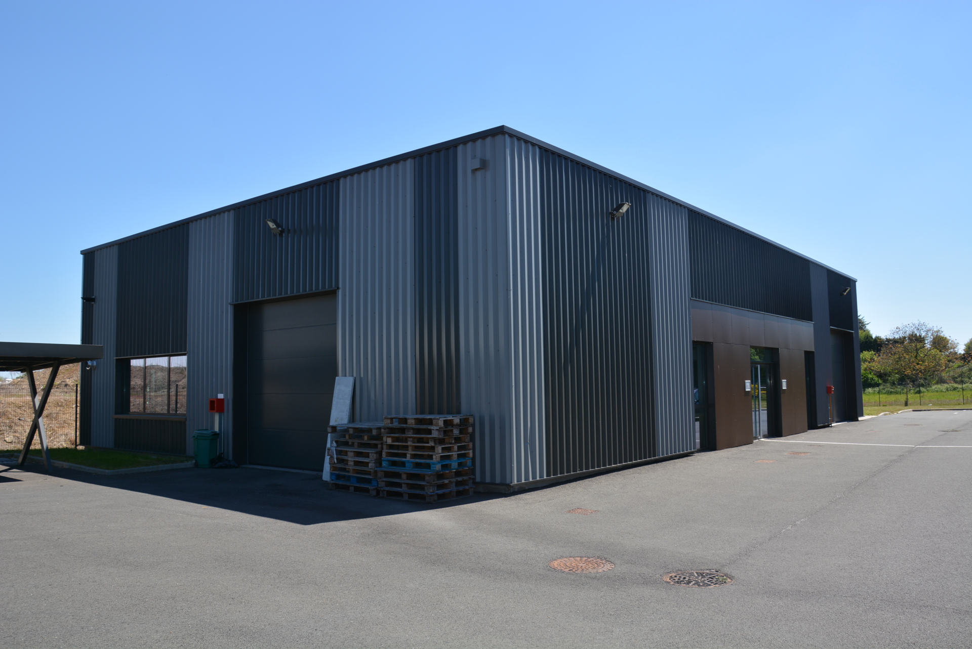 Bâtiment industriel avec porte de garage, palettes et extincteur.