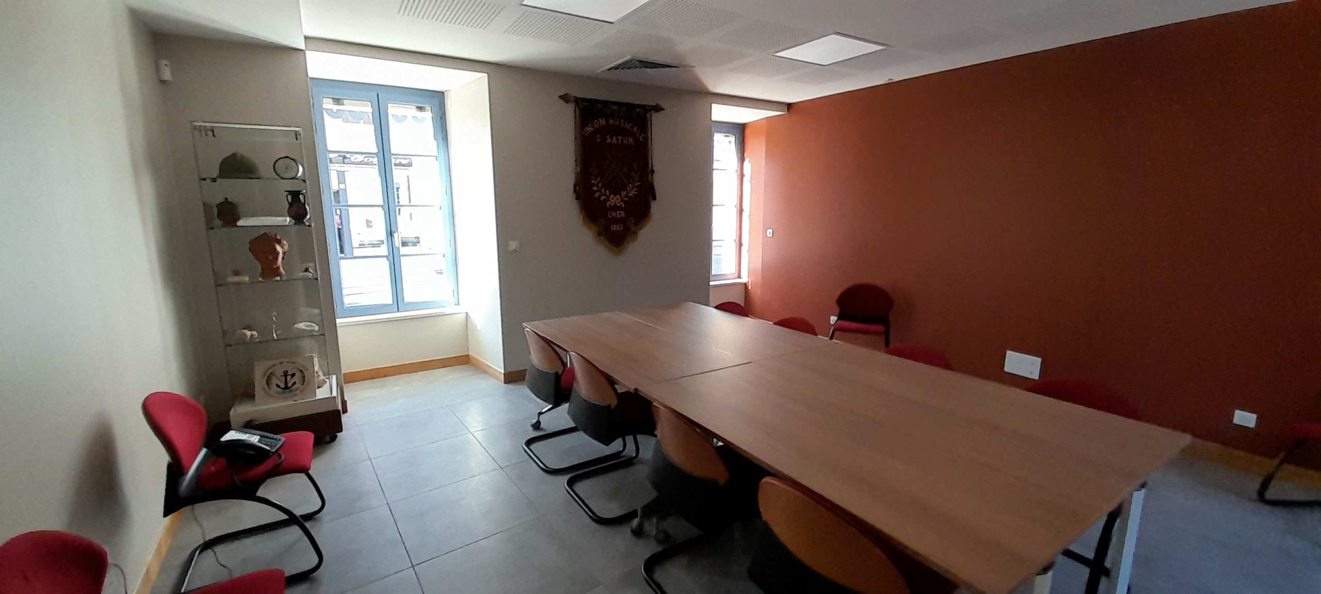 Salle de réunion avec table, chaises, vitrine d'exposition et drapeau mural