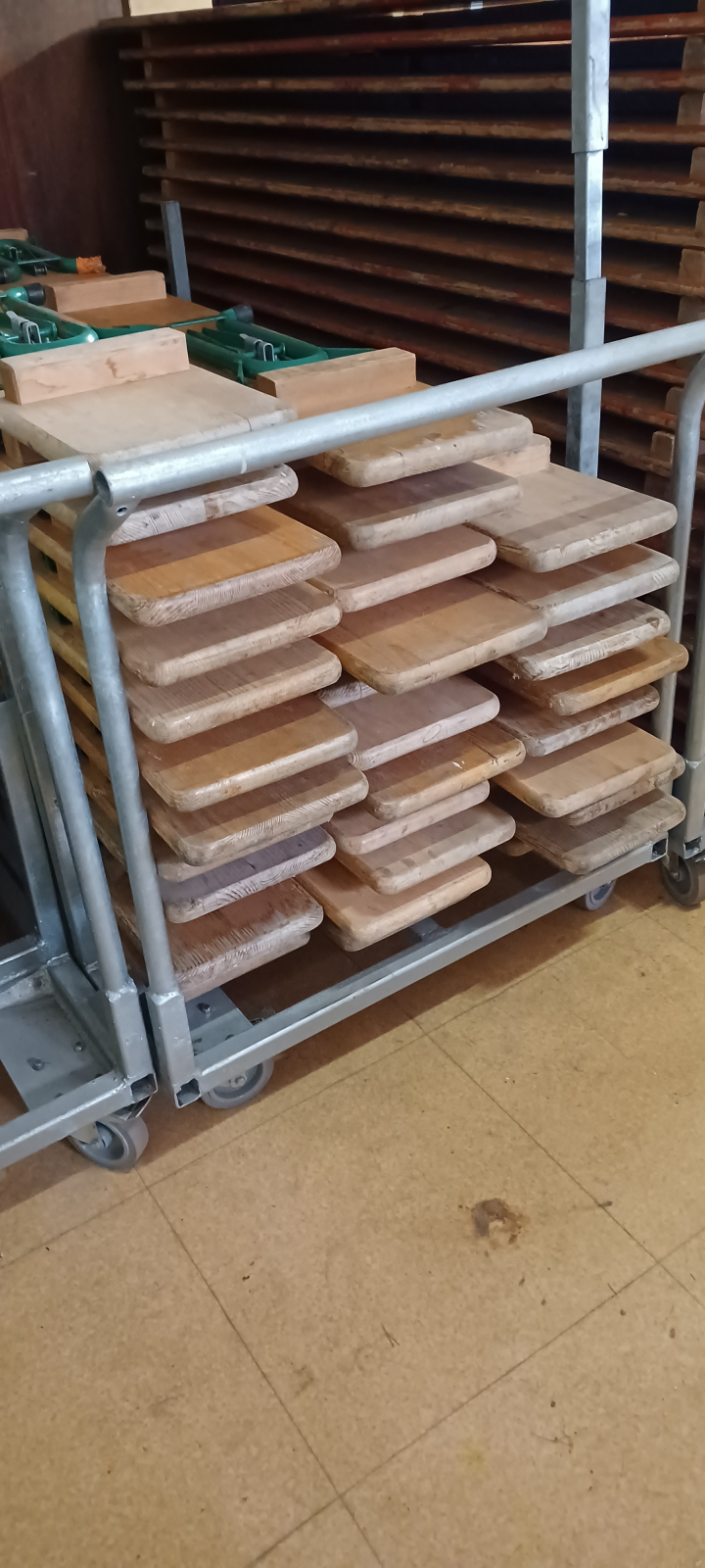 Chariot métallique avec piles de tables en bois.
