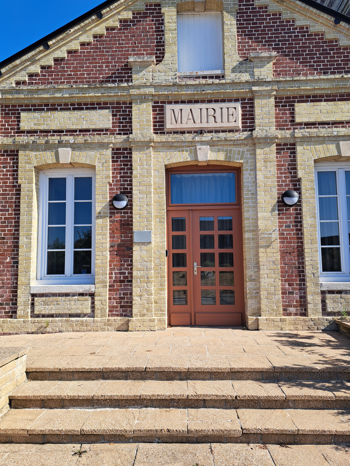 Mairie avec porte en bois, fenêtres et marches.