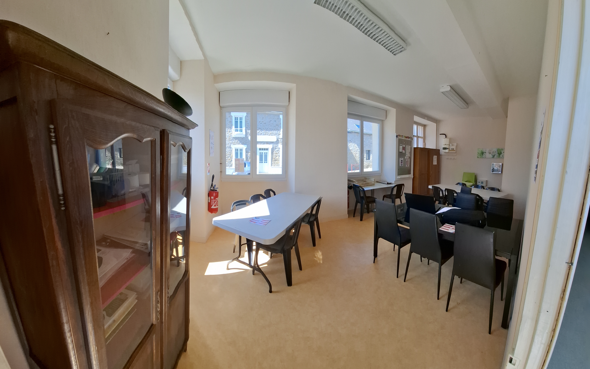 Salle avec table, chaises, armoire et fenêtres.