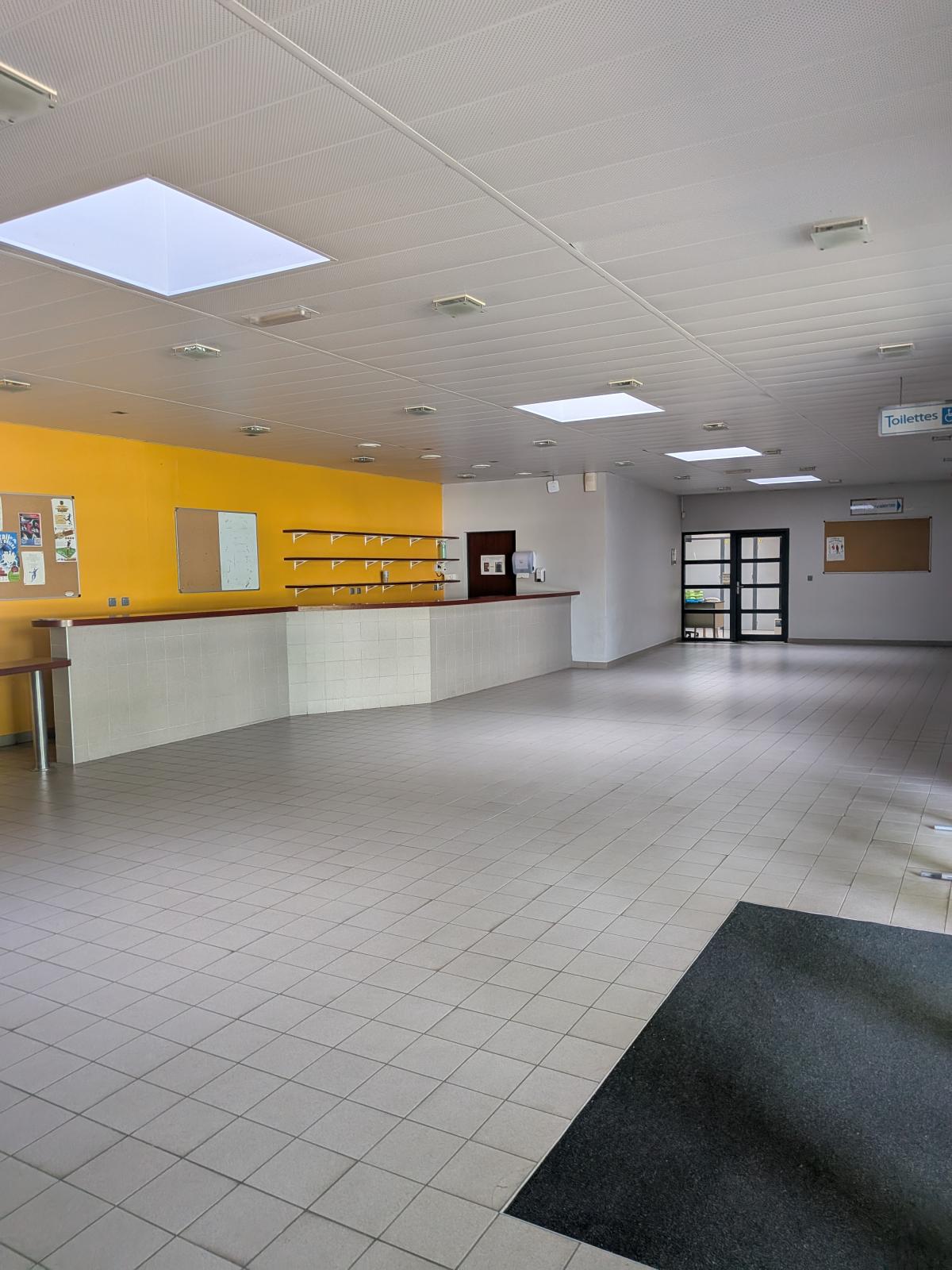 Réception avec comptoir, étagères, portes et tapis.