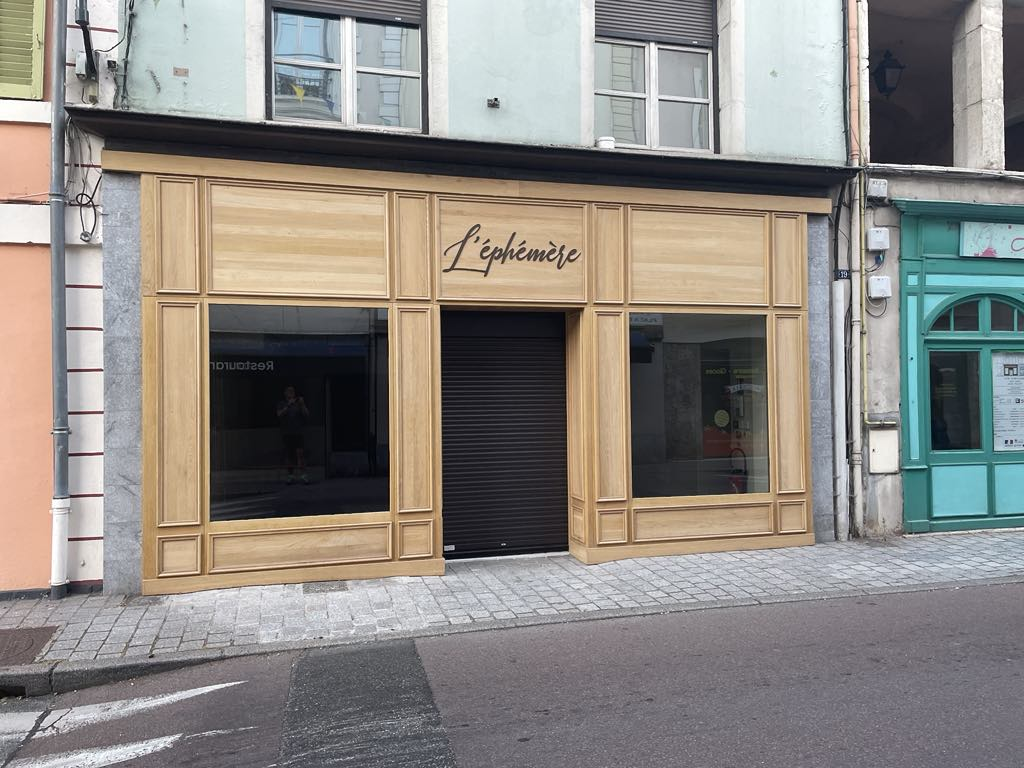 Boutique avec devanture en bois, vitrines et rideau métallique.