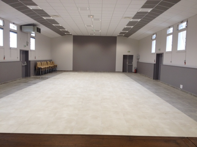 Salle vide avec rangée de chaises, projecteur, portes et fenêtres.