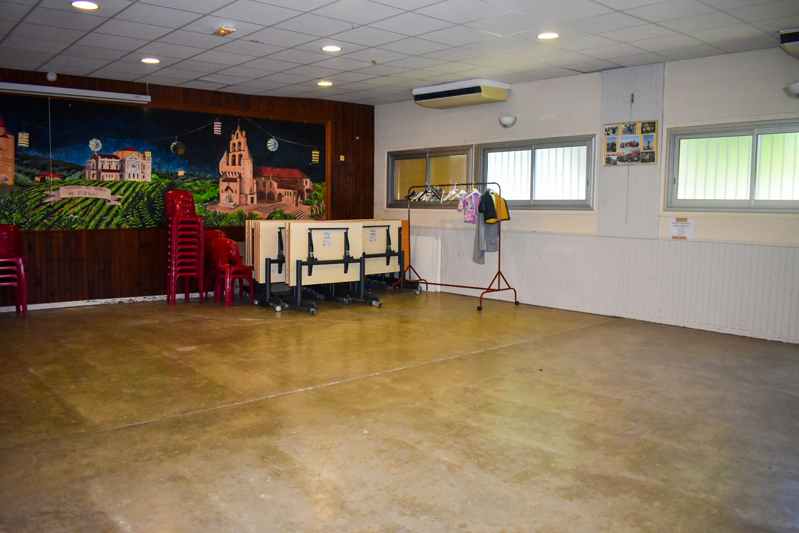 Salle avec chaises, table, étagère, porte-manteau, et peinture murale.
