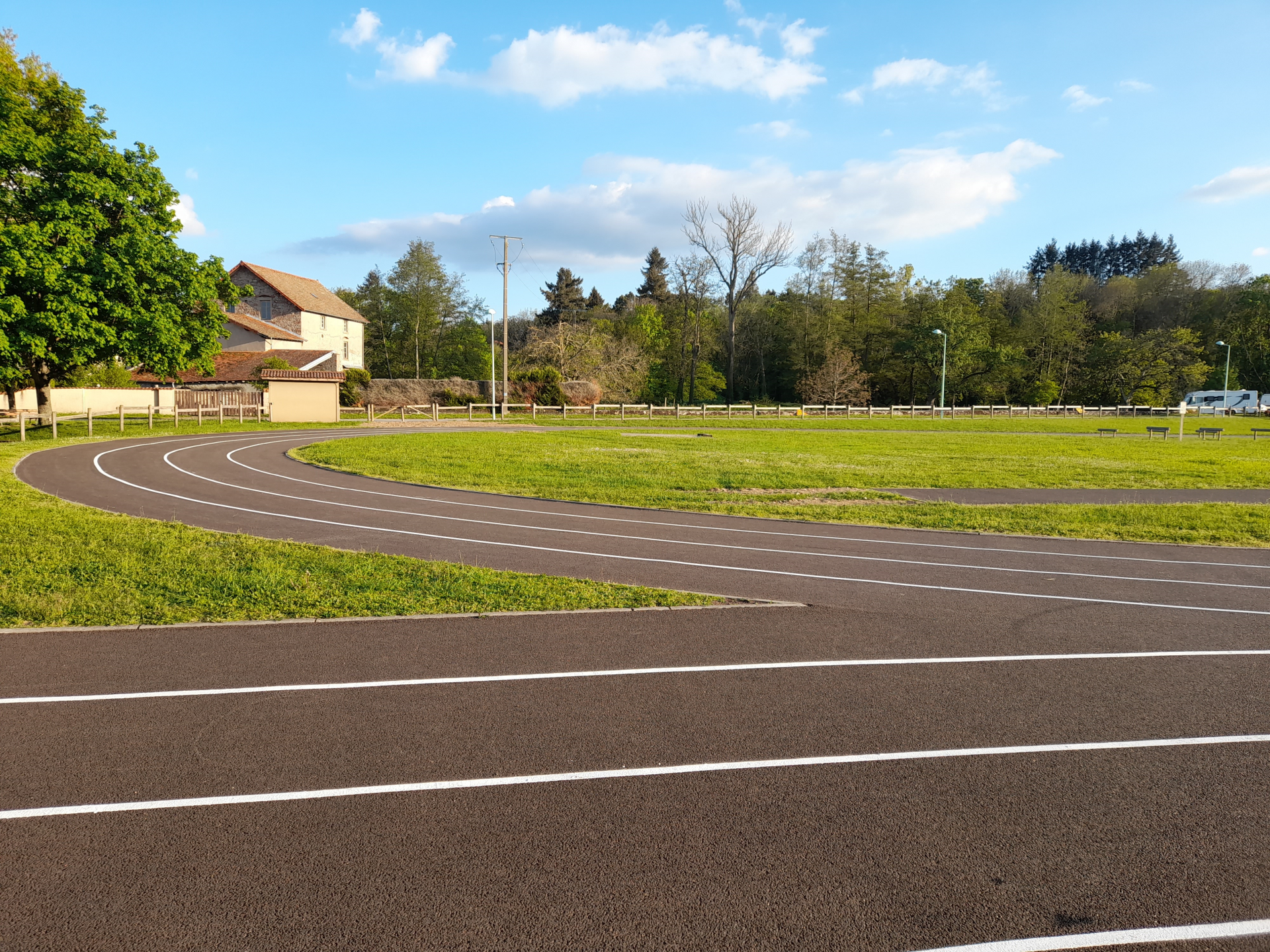 Parking avec lignes de marquage, pelouse, arbres, bâtiment et poteaux électriques.