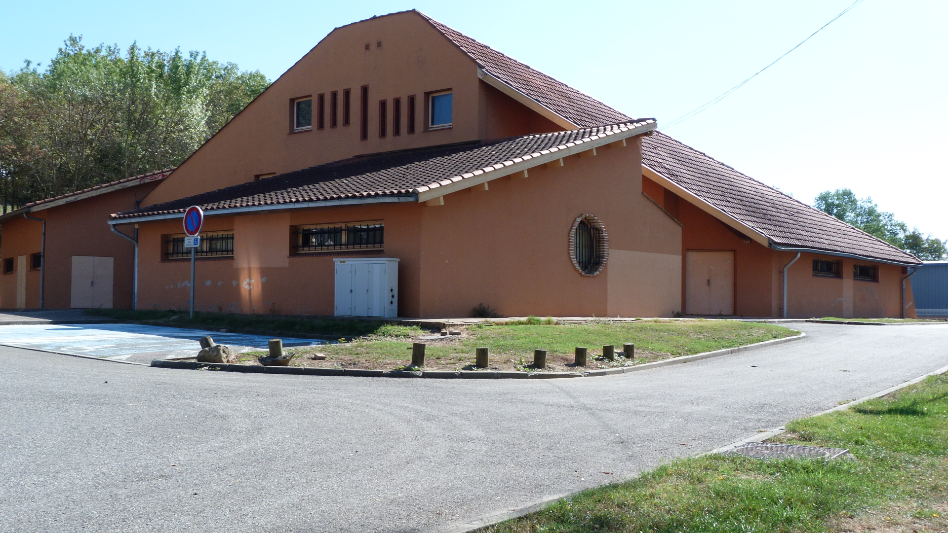 Bâtiment avec toit en tuiles, portes sectionnelles et panneau d'arrêt.