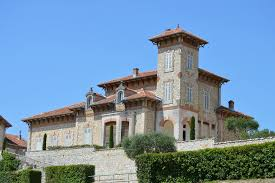 Maison de style méditerranéen avec tour, toit en tuiles rouges, murs de pierre et balustrade.