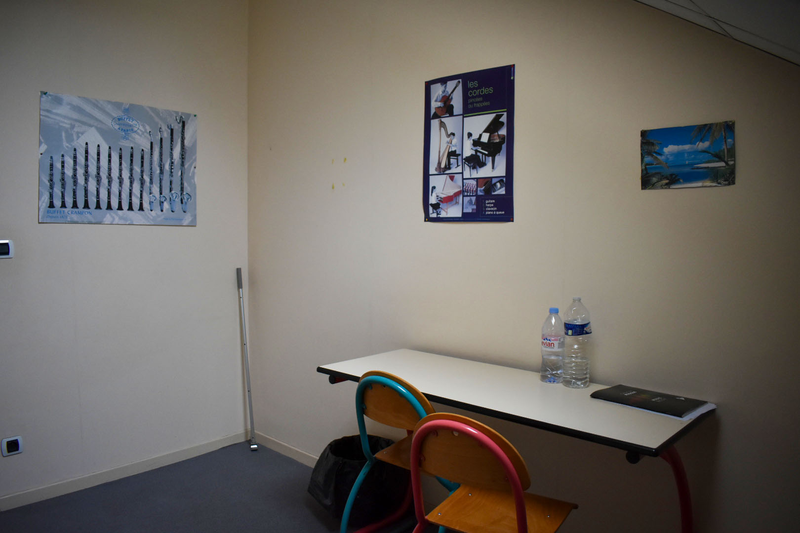 Pièce avec table, chaise, bouteille d'eau et trois affiches sur le mur.