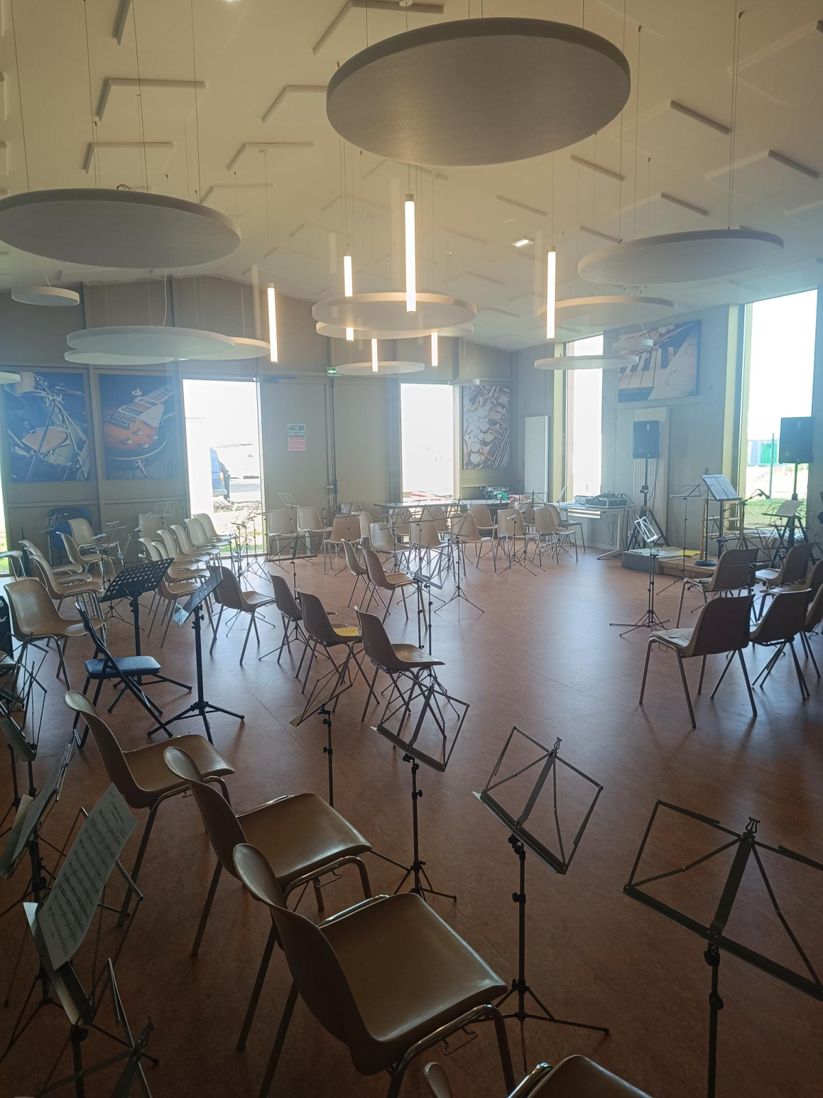 Salle avec chaises, pupitres, fenêtres, œuvres d'art murales et éclairage moderne.