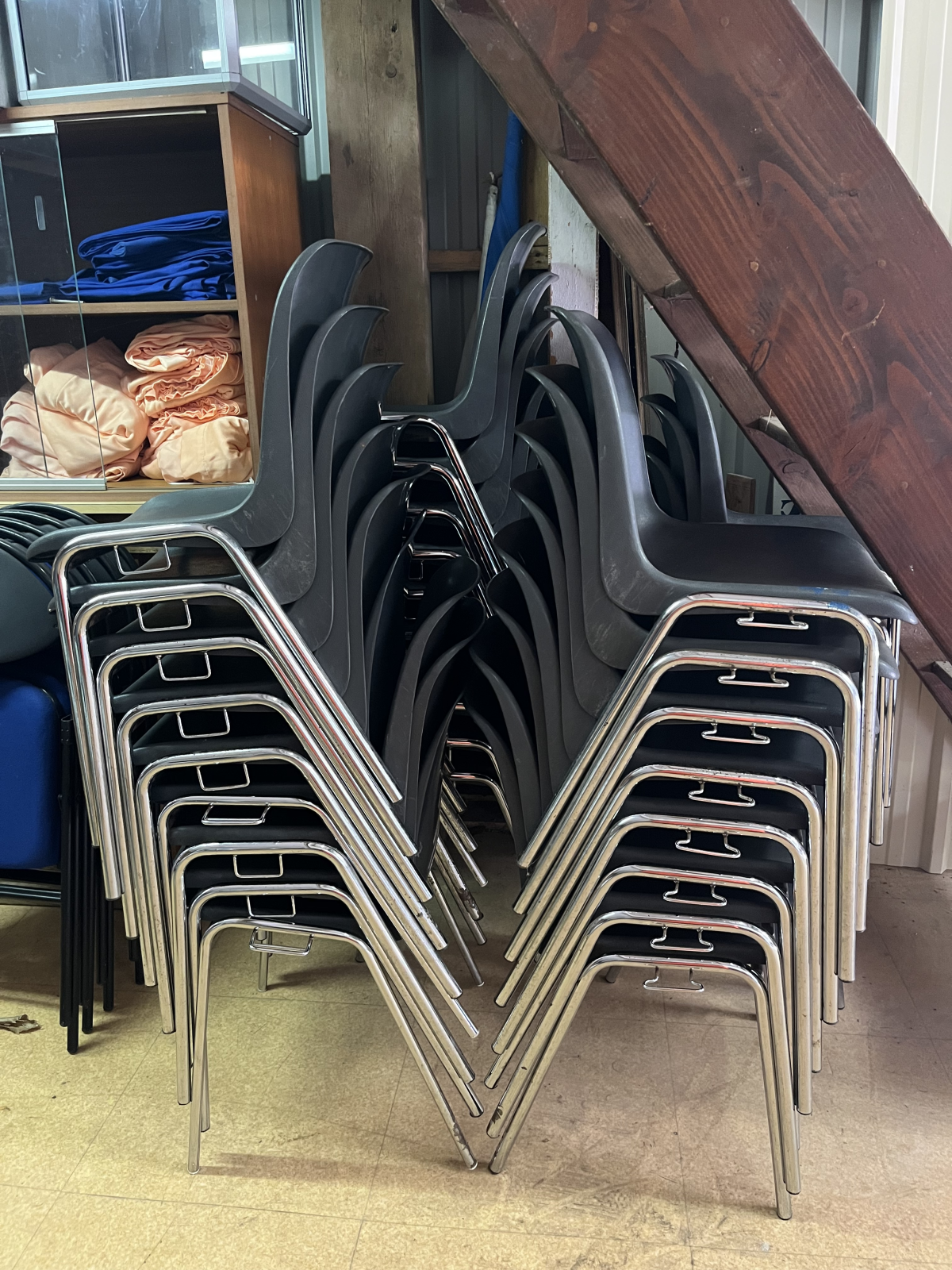 Chaises empilées avec table en bois et étagères en arrière-plan.