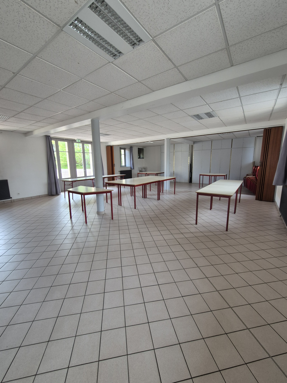 Salle avec tables, chaises, et colonnes.