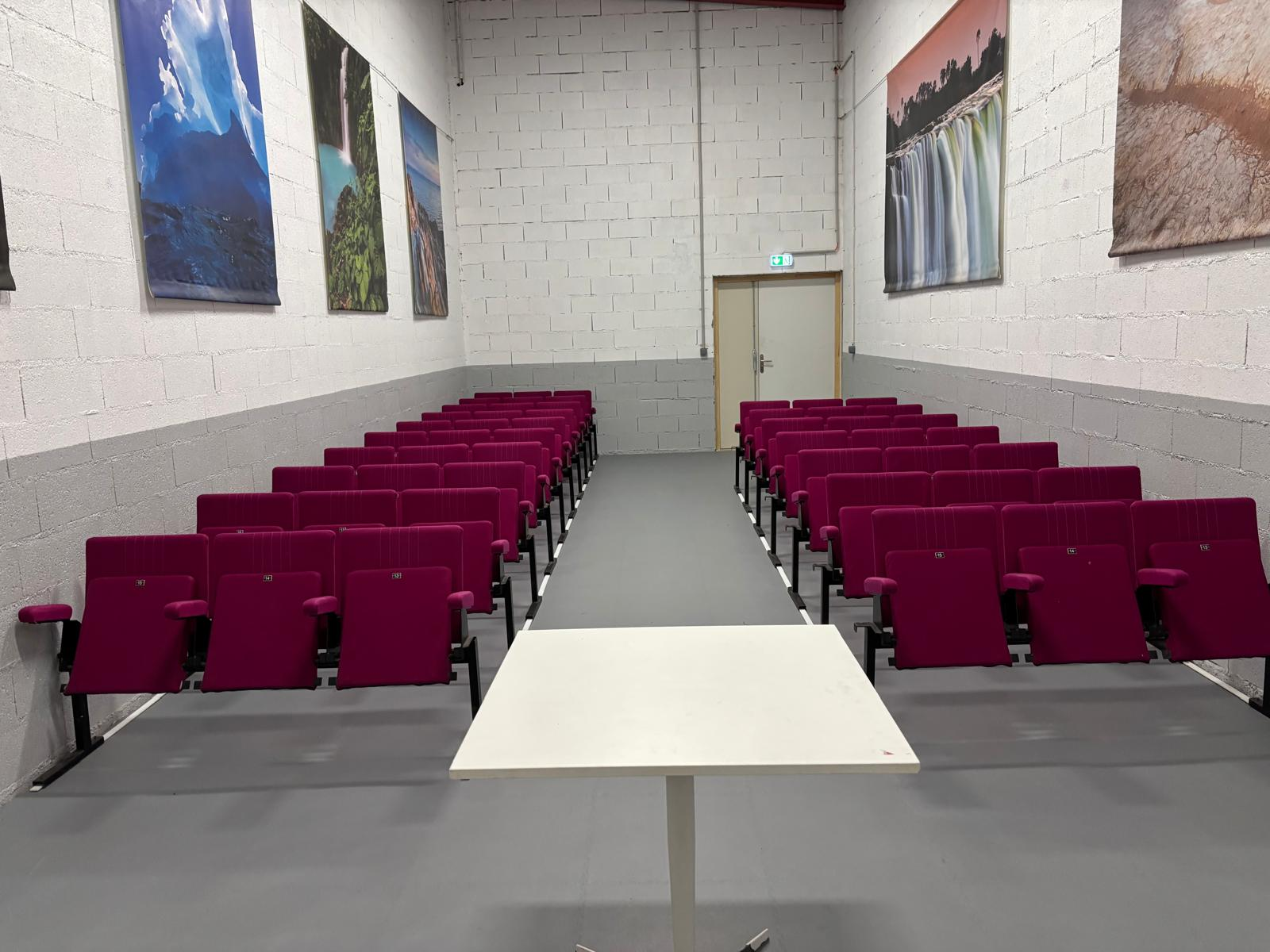Salle de classe avec chaises, table et tableaux aux murs.