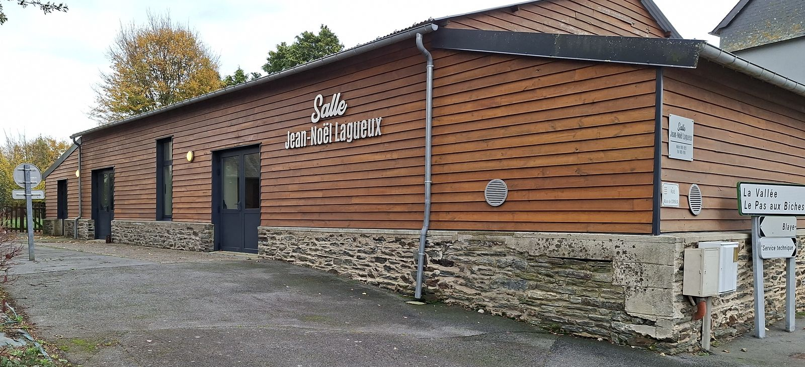 "Bâtiment extérieur avec façade en bois, porte, fenêtres, et panneaux indicateurs."