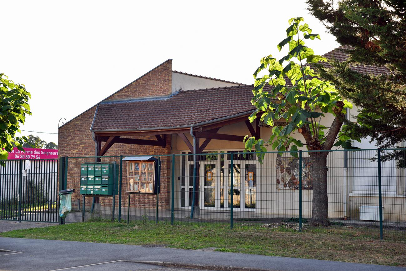 Bâtiment avec toit en tuiles, porte vitrée, arbre et clôture.