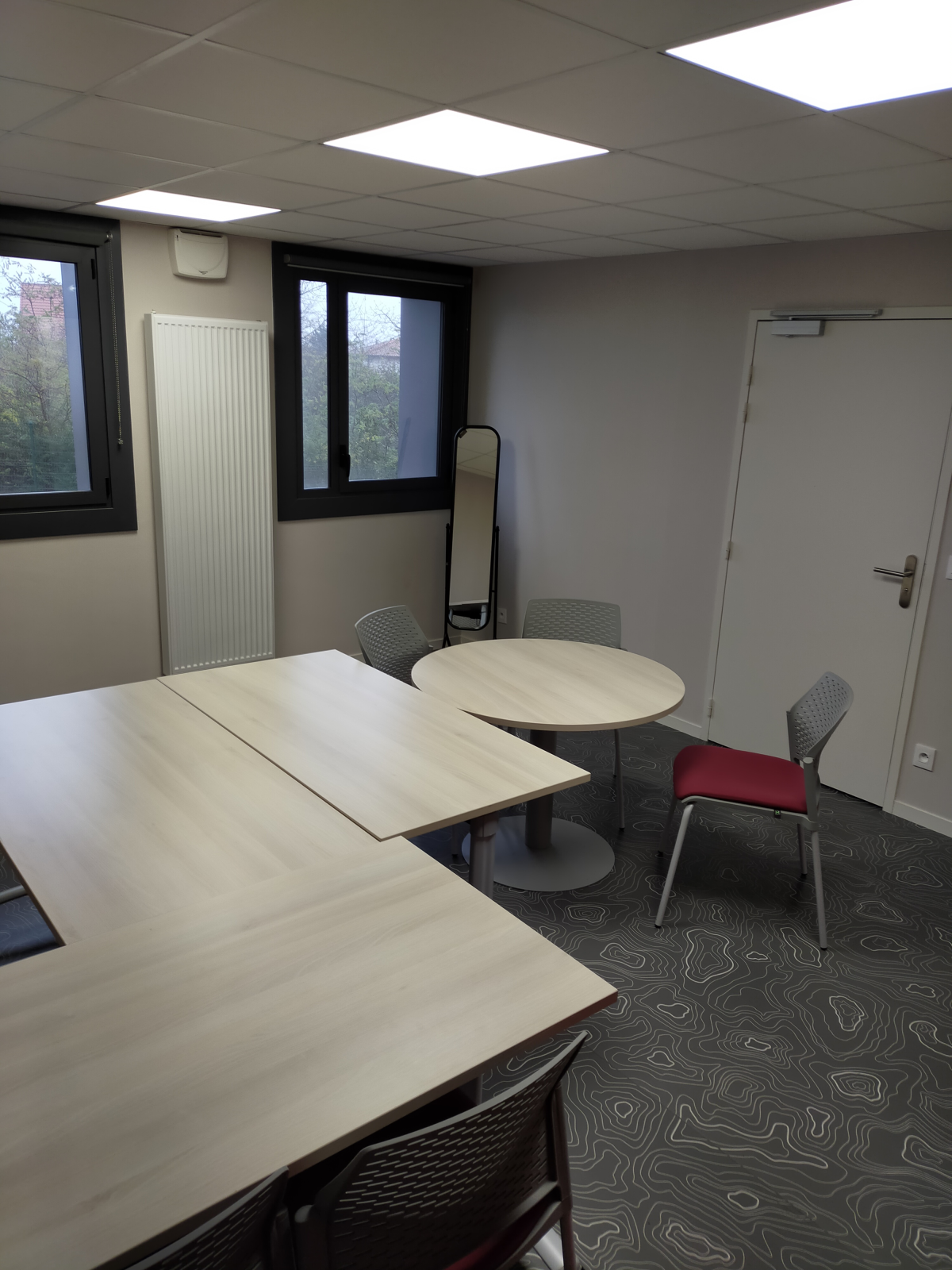 Salle avec tables, chaises et moquette.