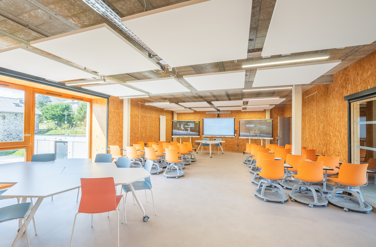 Salle de classe avec tables, chaises, tableau blanc et projecteur.