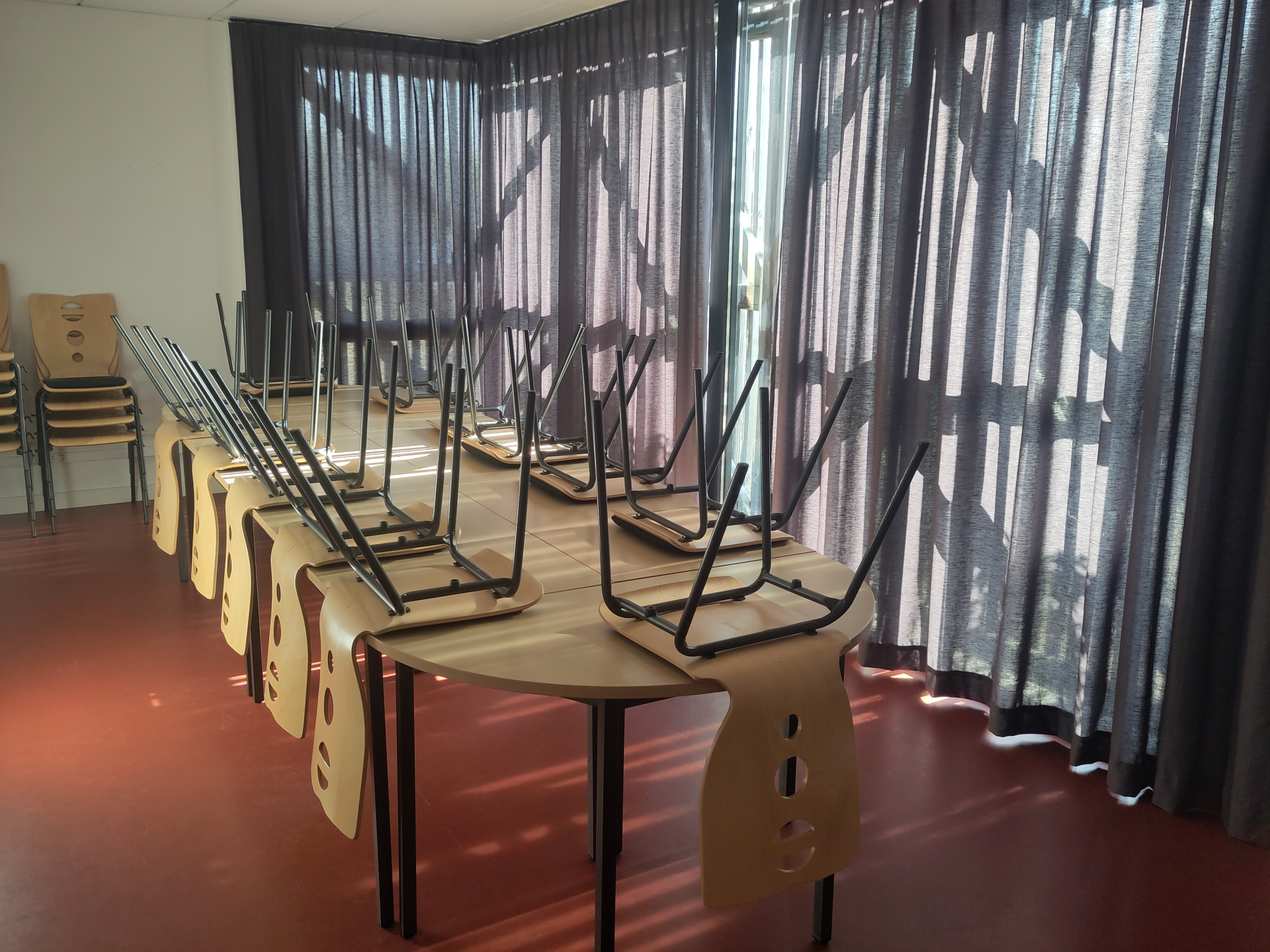 Salle avec tables, chaises, rideaux et fenêtres.