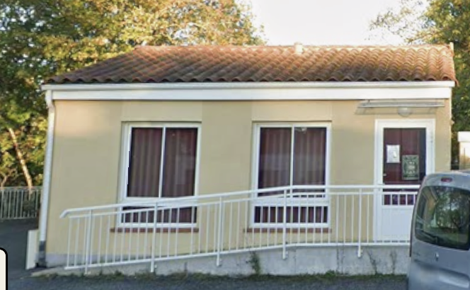 Maison avec toit en tuiles, murs beiges, trois fenêtres avec rideaux bruns, porte d'entrée, rampe blanche et voiture garée.