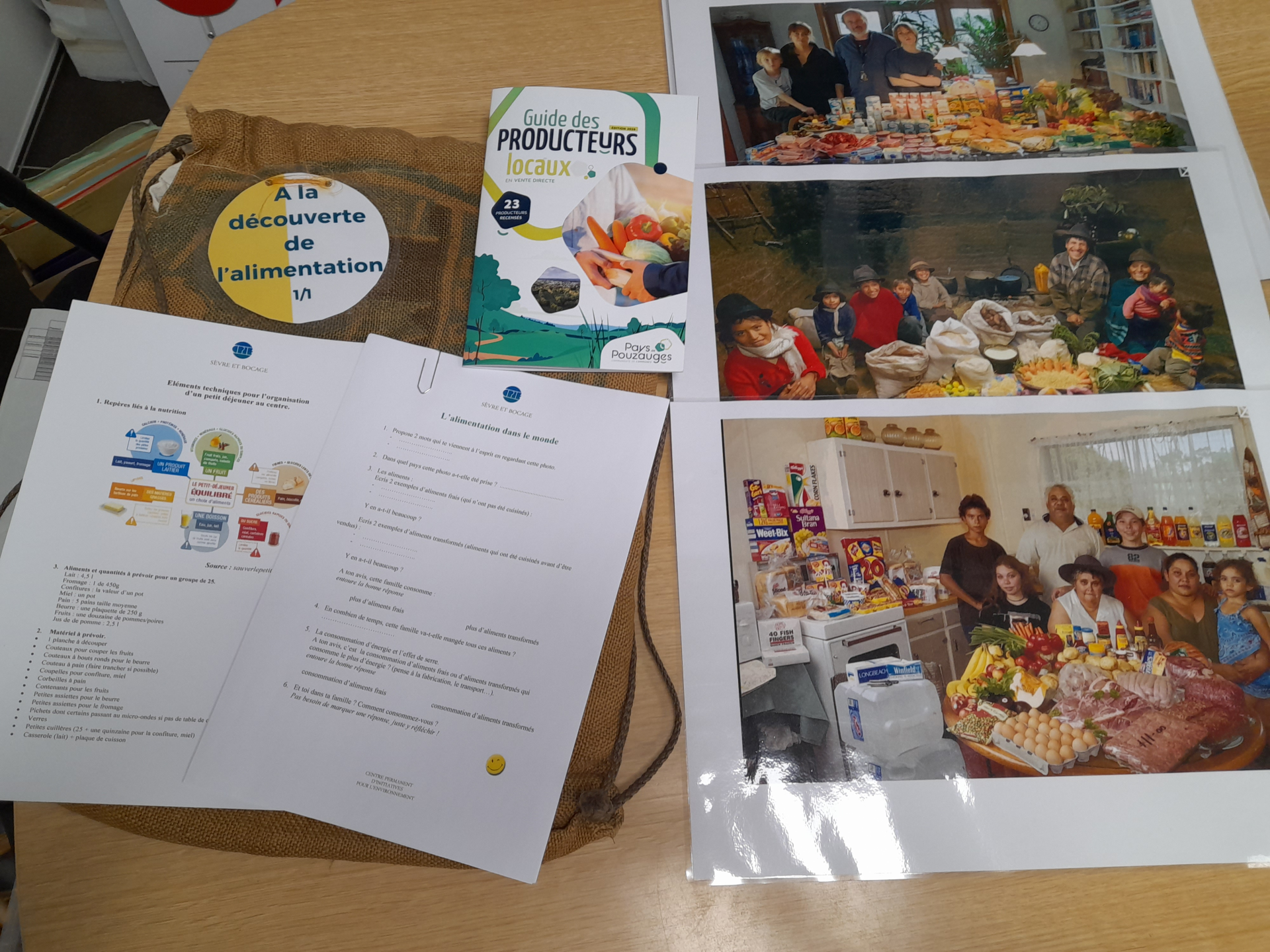 Sur une table, brochures, photos, et documents sur l'alimentation et les producteurs locaux.