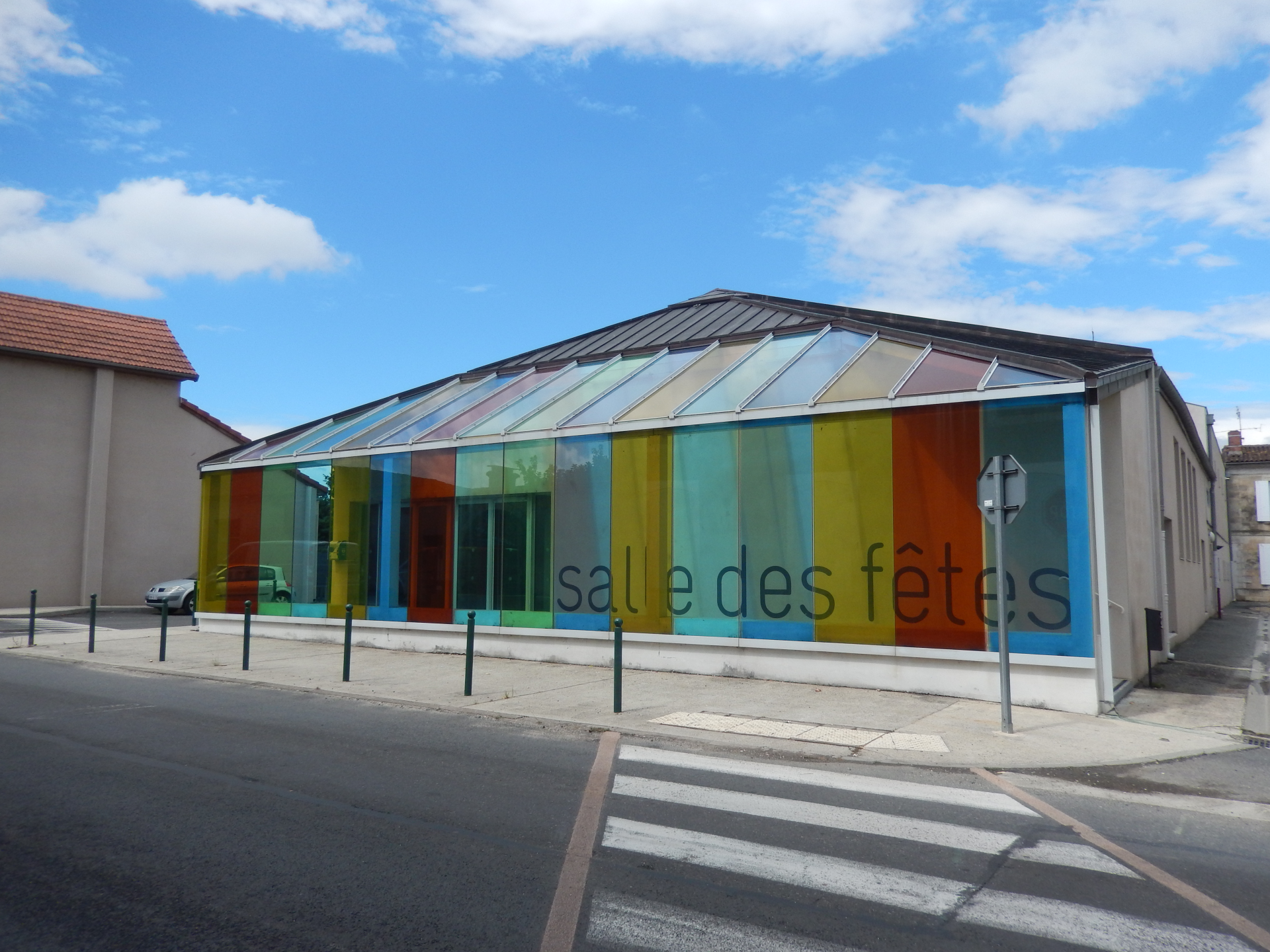 Bâtiment avec façade vitrée colorée, porte et escalier extérieur.