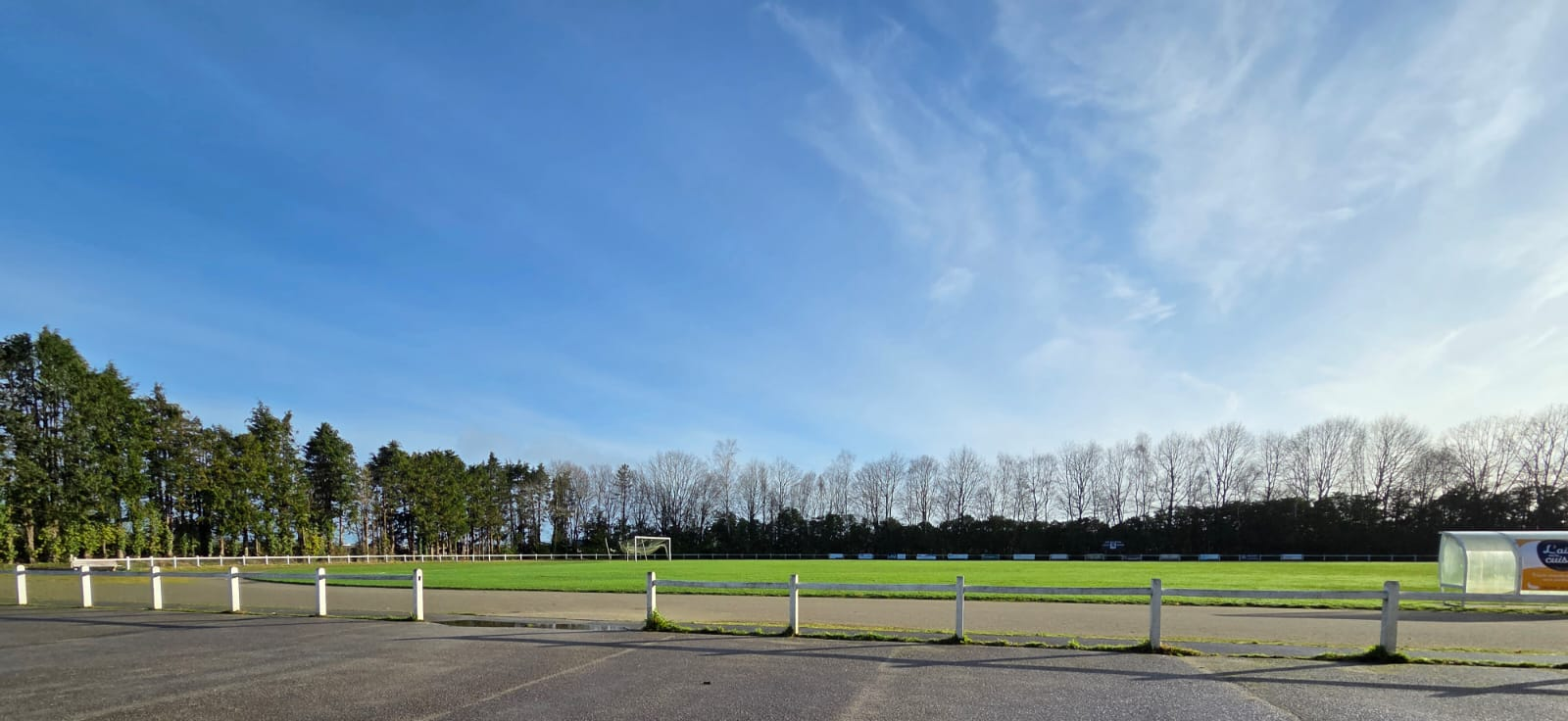 Terrain de sport avec parking, clôture et but de football.