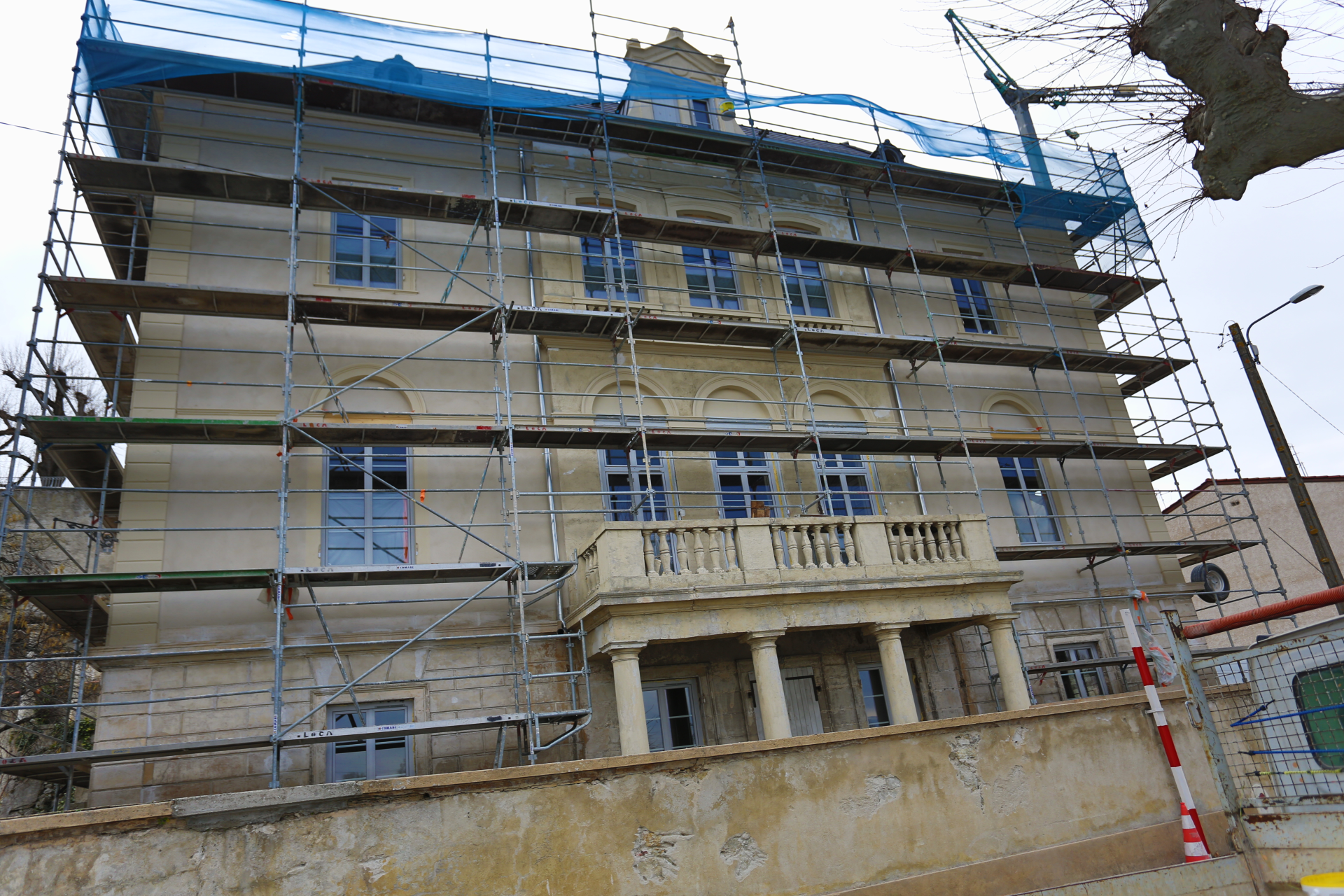 Bâtiment en rénovation avec échafaudages, fenêtres et balcons.