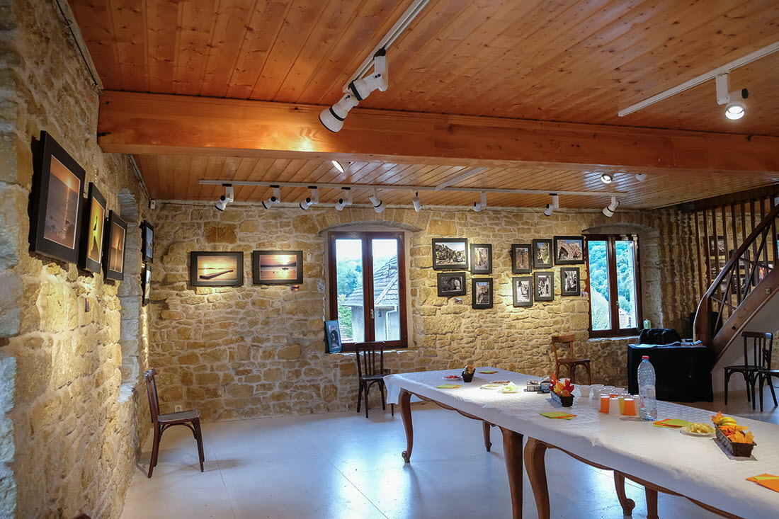Pièce avec table, chaises, tableaux et escalier en colimaçon.