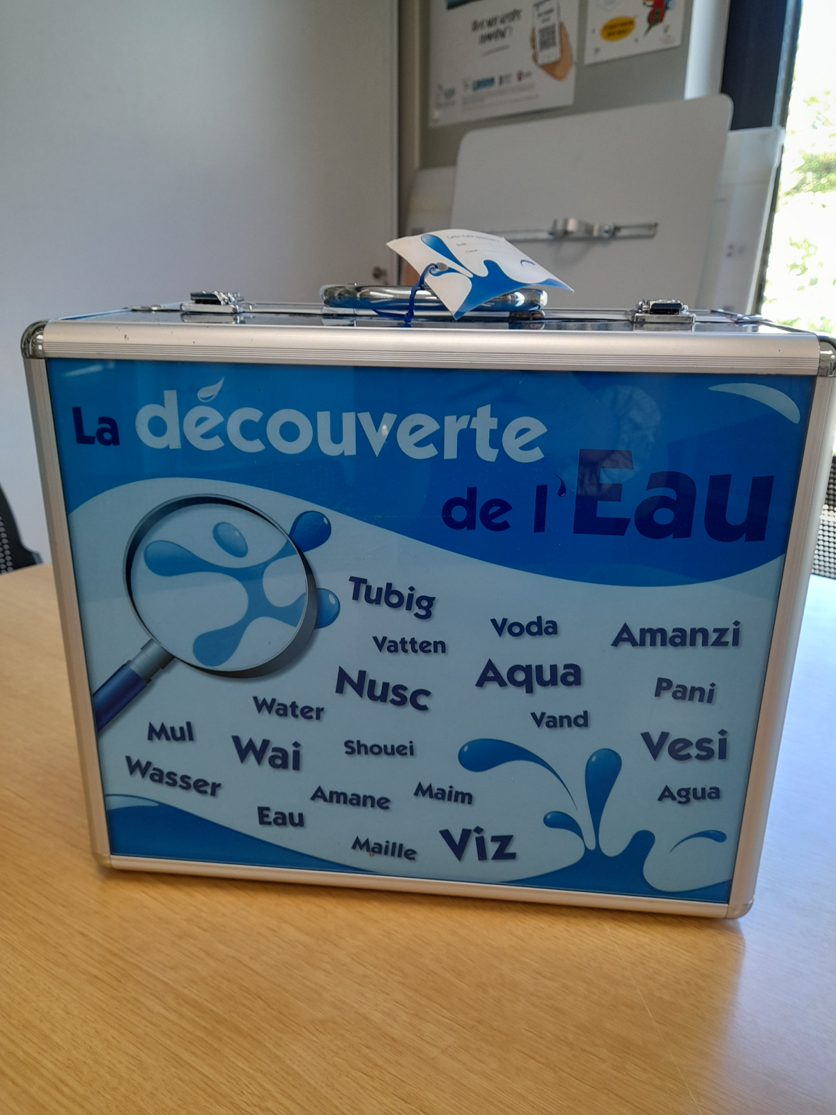 Une valise éducative sur l'eau avec des mots pour "eau" dans différentes langues.