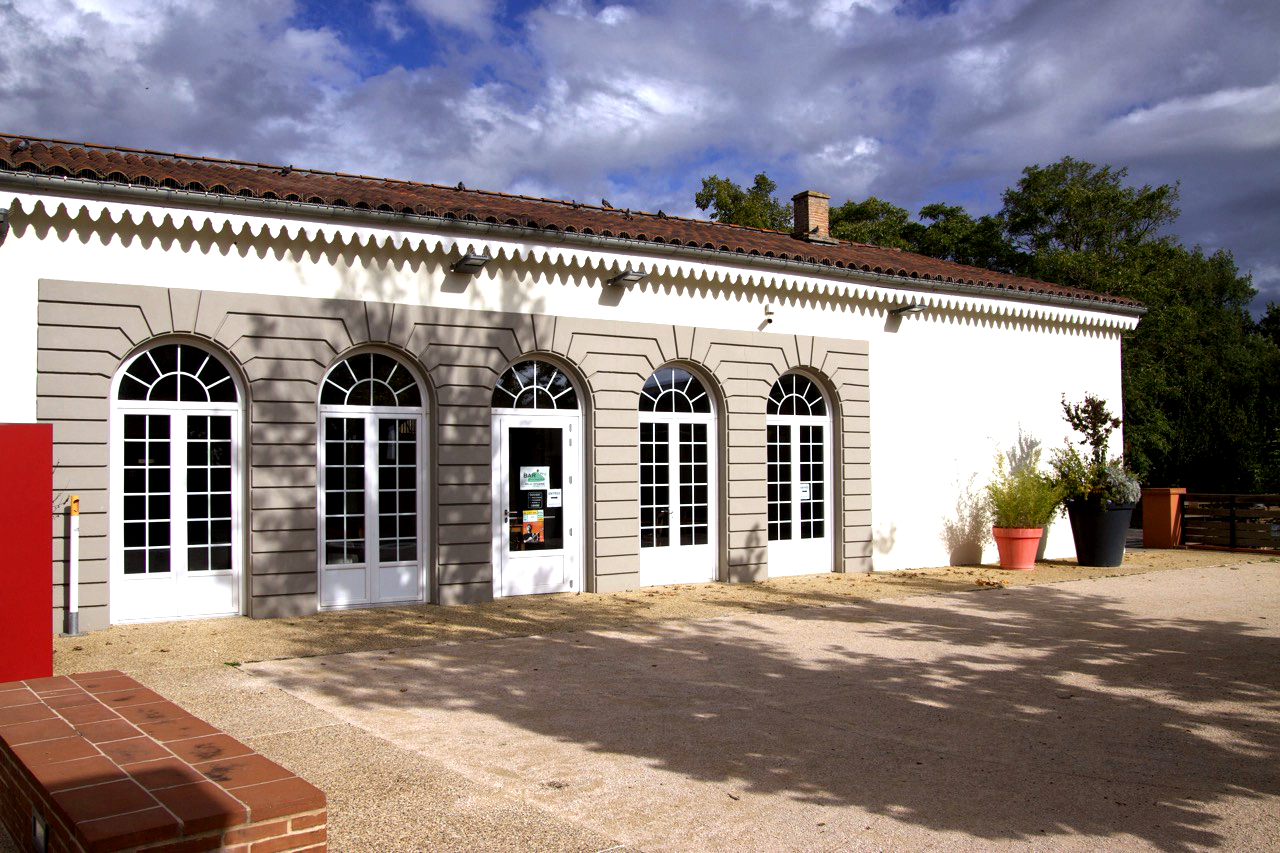 Bâtiment avec fenêtres, porte, pots de fleurs et banc.