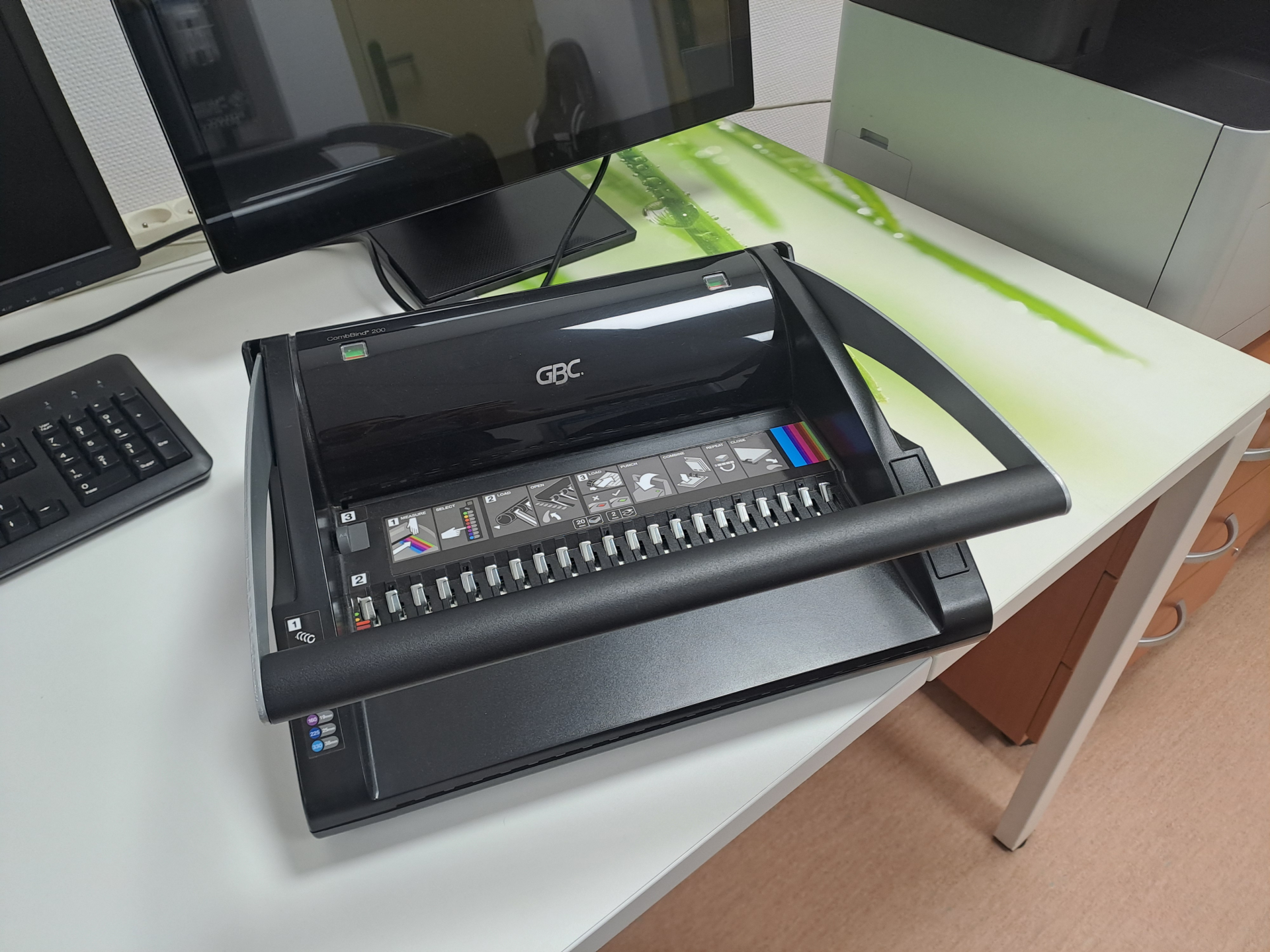 Bureau avec imprimante, clavier, écran et téléphone.