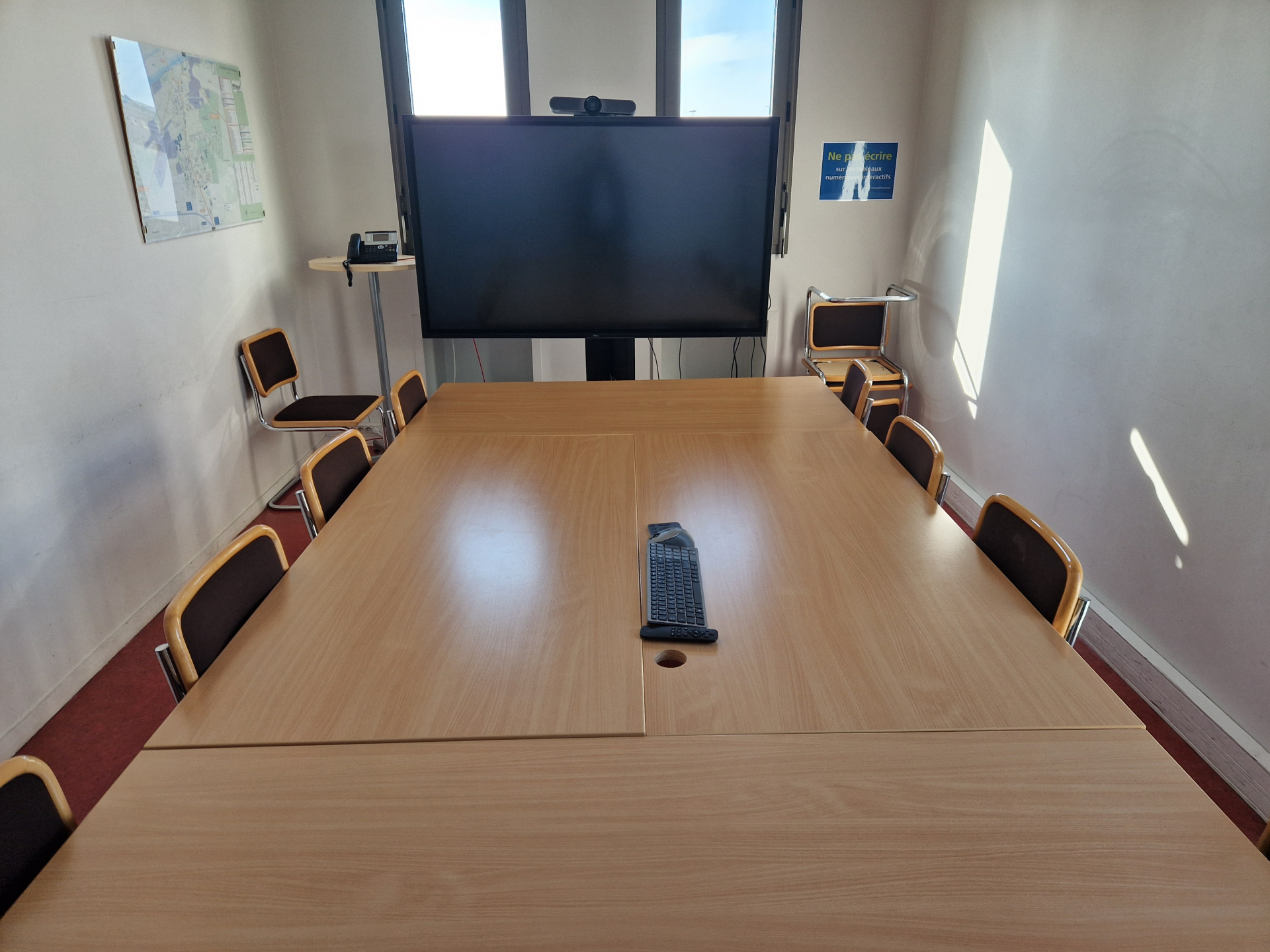 Salle de réunion avec table, chaises et écran.