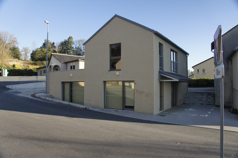 Maison moderne avec garage, fenêtres, porte et escalier menant à l’entrée.