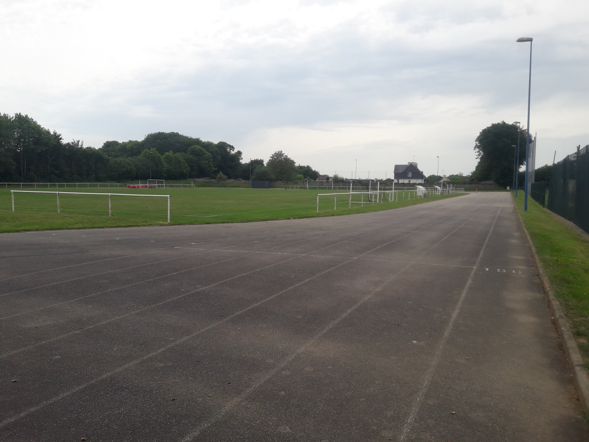 Terrain de sport avec piste d'athlétisme, pelouse et but de football.