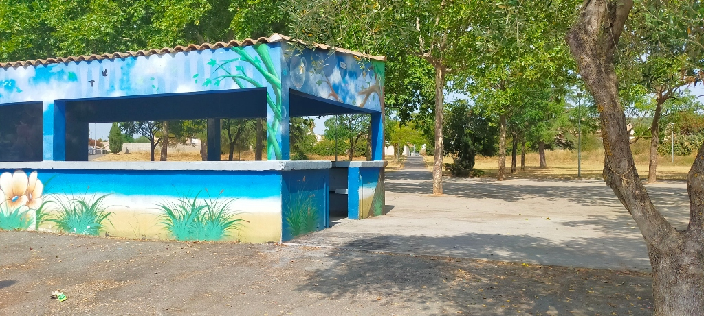 Structure extérieure peinte avec arbres et terrain en terre battue.
