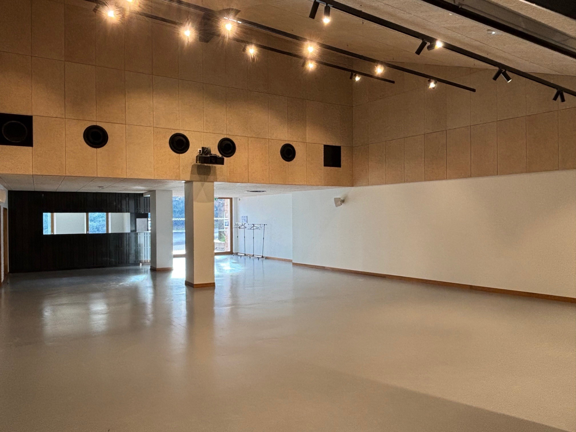 Salle vide avec éclairage, haut-parleurs, et porte vitrée.