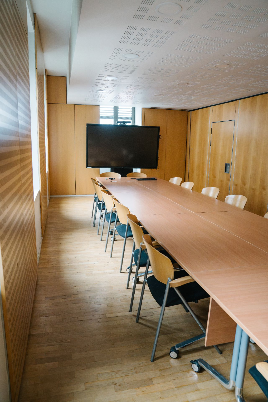 "Salle avec table, chaises, écran et porte."