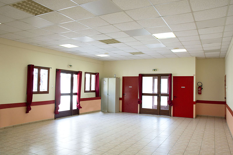 Salle vide avec portes, fenêtres, extincteur et placard.