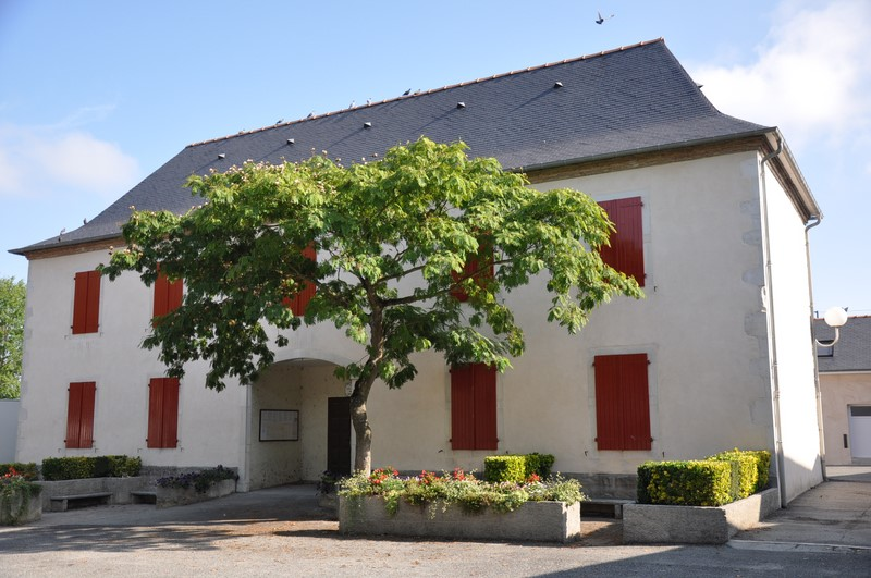 Maison avec volets rouges, arbre et buissons.