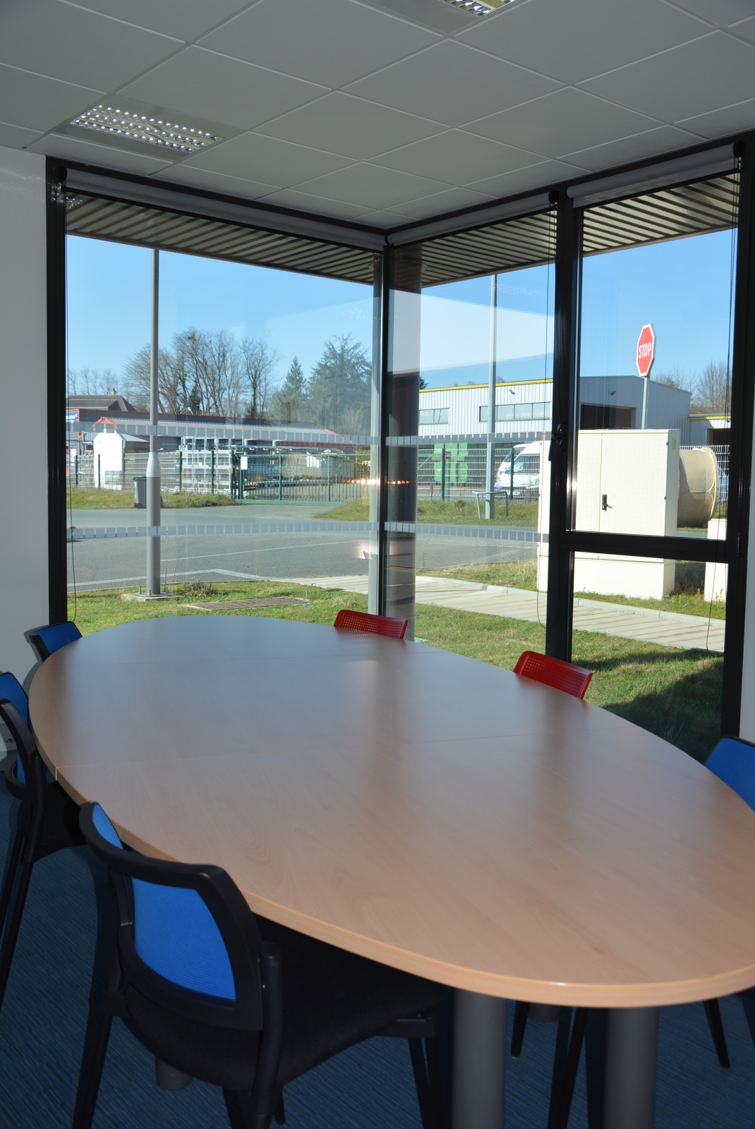 Salle ovale avec table, chaises et fenêtres vue sur l'extérieur.