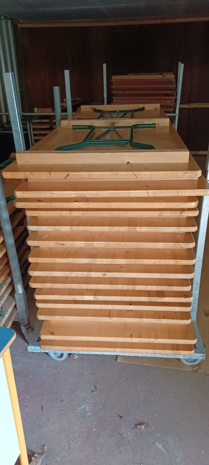 Chariot avec tables en bois empilées.