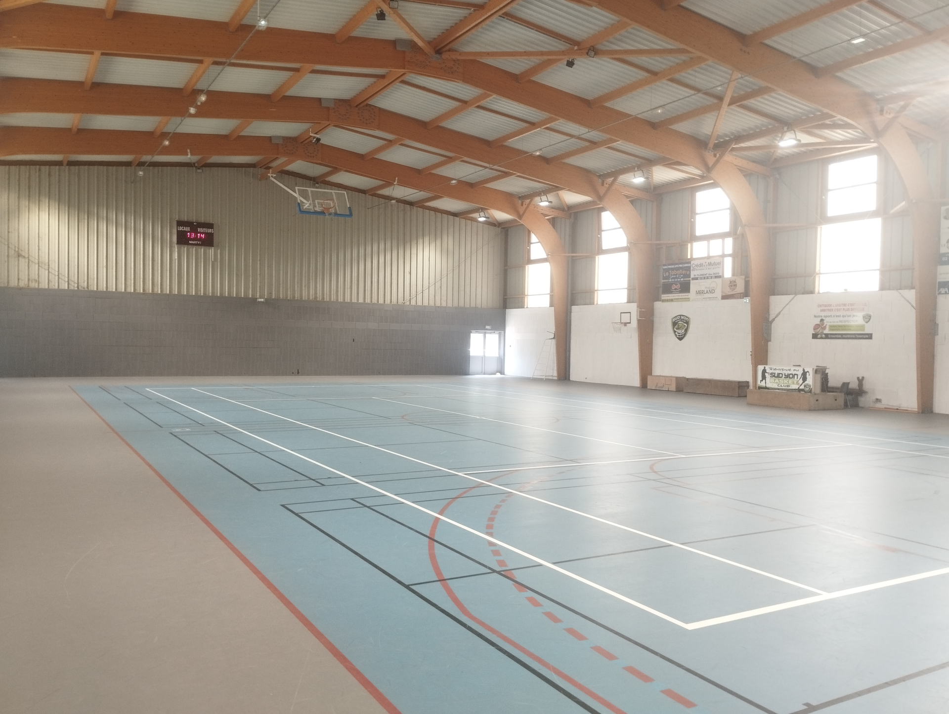 Salle de sport avec panier de basket, terrain de basket et bancs.