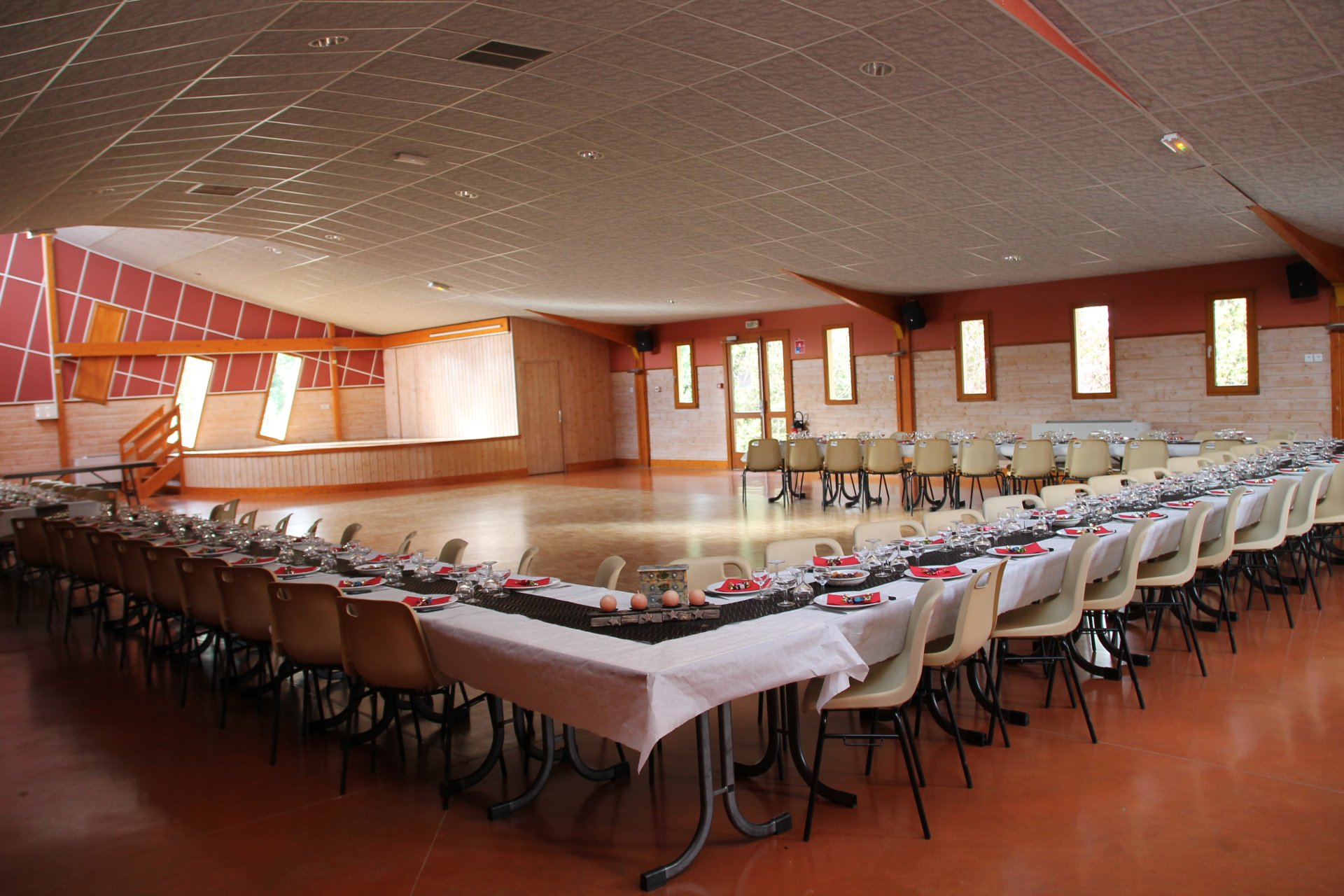 Salle avec tables, chaises, nappes, verres, couverts.