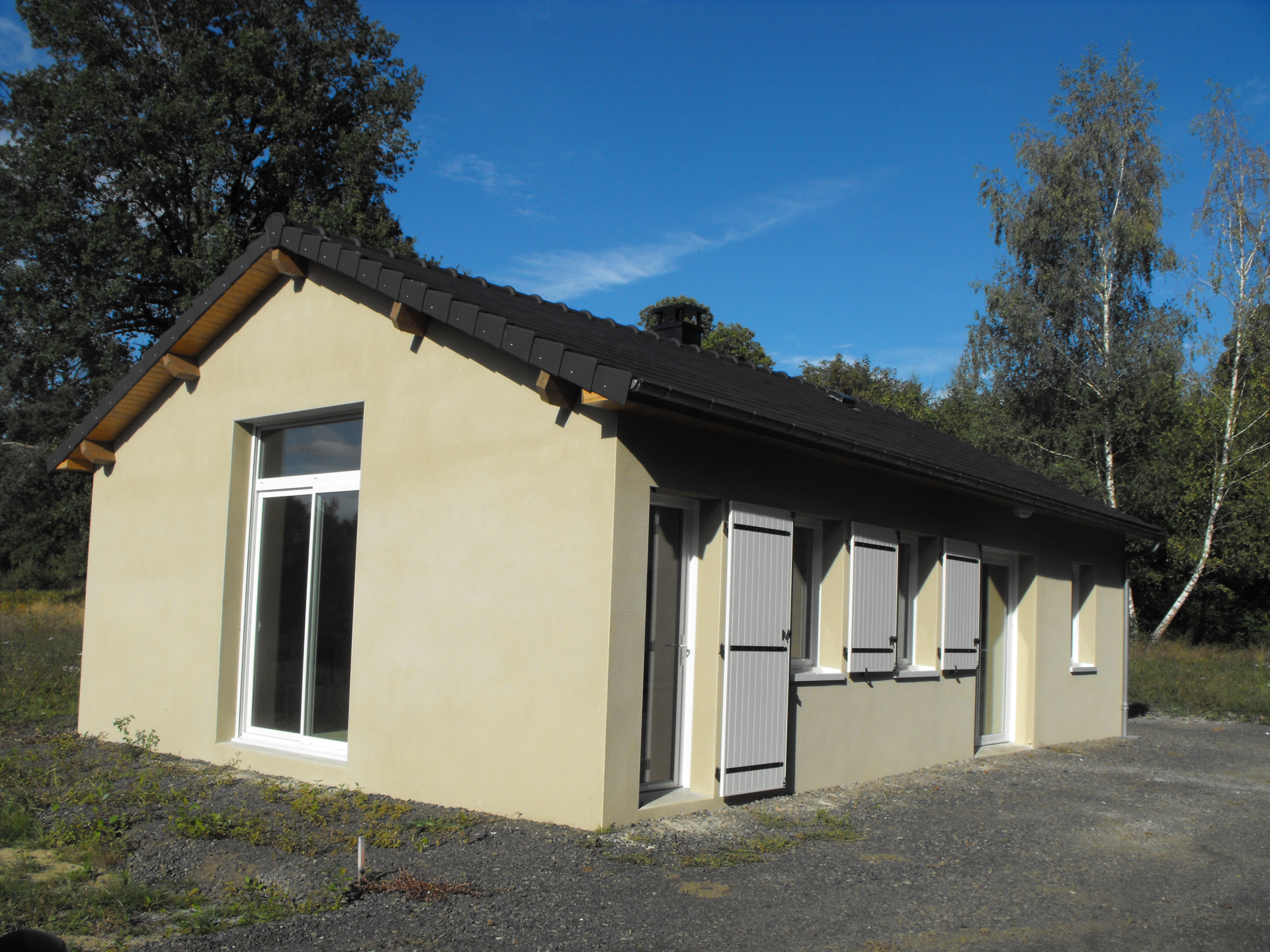 Bâtiment jaune avec toit noir, fenêtres et portes.