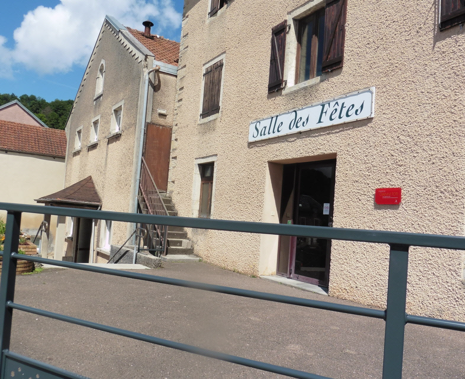 Bâtiment avec escalier extérieur, entrée principale et panneau "Salle des Fêtes".
