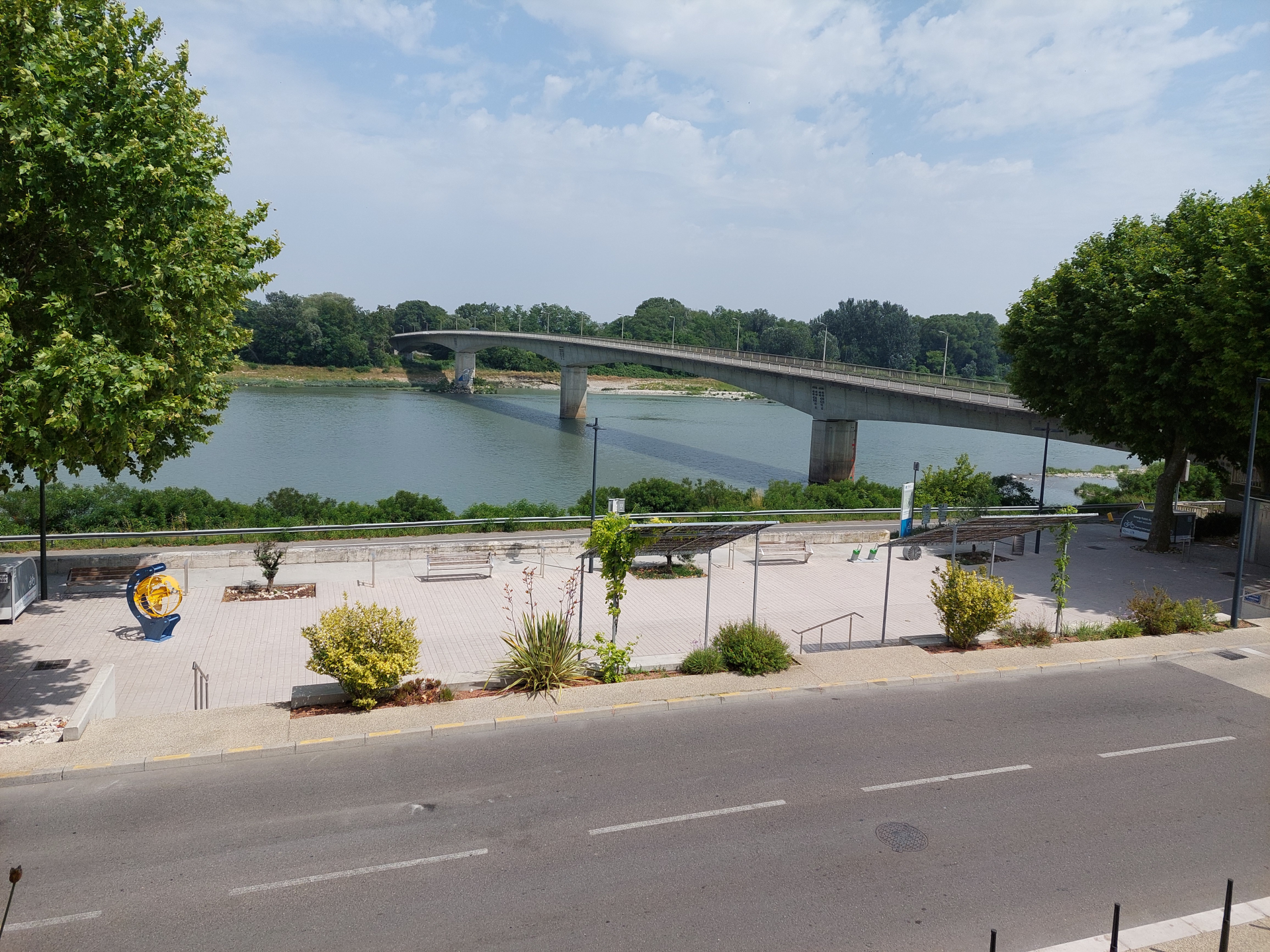 Vue de pont sur rivière, route et espace vert.